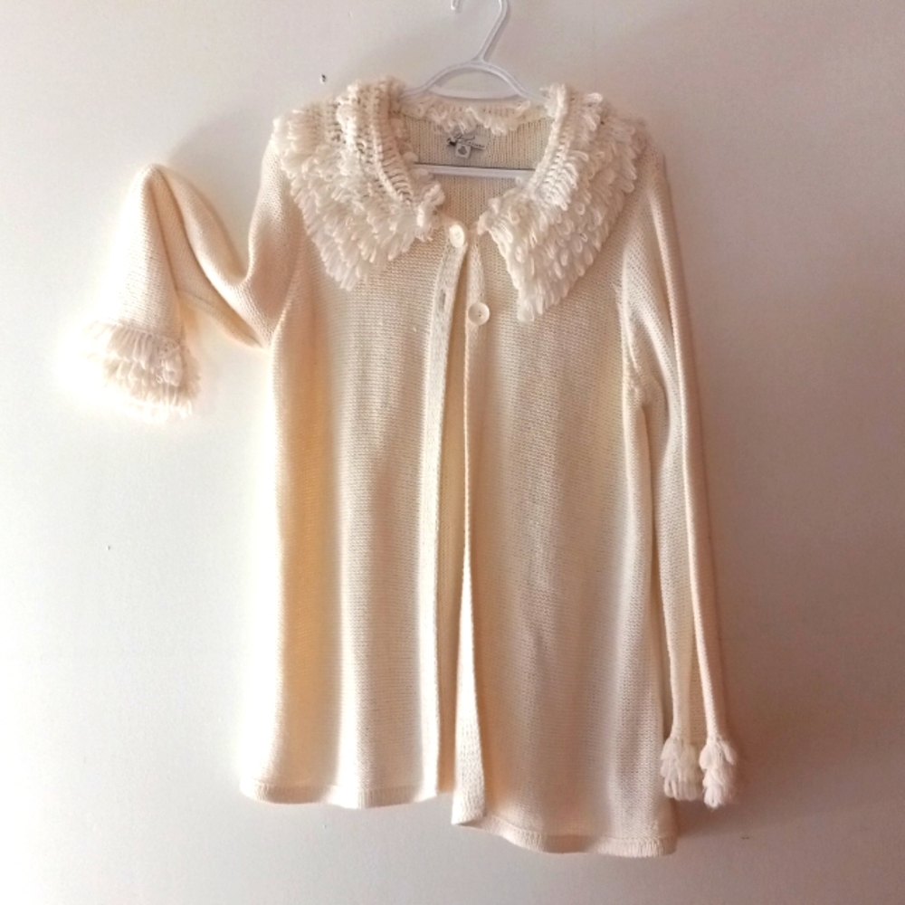 Warm cream over sweater, two buttons, ruffled yarn at neck and cuffs.